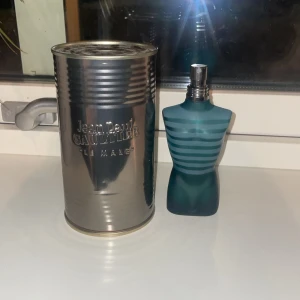 Jean Paul Gaultier Le Male Parfym - Säljer en ikonisk Jean Paul Gaultier Le Male parfym i en unik flaska formad som en manlig torso. Flaskan är blå med horisontella ränder och kommer i en metallisk burk. Perfekt för den som vill ha en klassisk och maskulin doft. Det är ungefär 55ml kvar i den av 75ml. Ny pris 1100kr