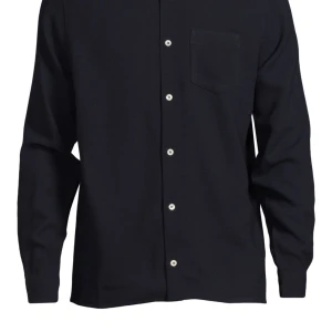 Svart skjorta från Séfr - Stilren svart skjorta från Séfr med klassisk krage och knappar framtill. Skjortan har en bröstficka och långa ärmar, perfekt för en elegant look. Passar perfekt för både vardag och när du vill klä upp dig inför något extra speciellt. Skjortan är i näst intill nyskick och har knappt blivit använd.