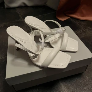 Vita klackskor - Säljer för att jag inte har fått andvändning av dom och därför är dom helt nya. Köptes på ASOS förra året så dom finns inte kvar på hemsidan. Smala remmar. De har en fyrkantig tå. 💗