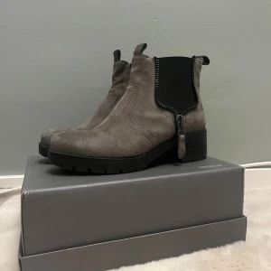 Grå mocka boots med dragkedja - Snygga grå boots i mocka med dragkedja på sidan. De har en robust sula och elastiska paneler för enkel passform. Perfekta för en stilren look.