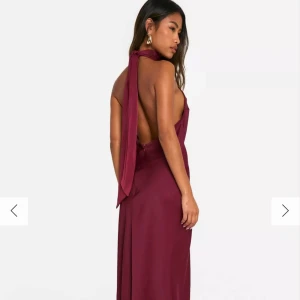 Vinröd balklänning  med öppen rygg - HELT NY PRISLAPP PÅ Elegant vinröd långklänning i satin med hög krage och öppen rygg. Klänningen har en smickrande passform och är perfekt för speciella tillfällen. Perfekt till balen 