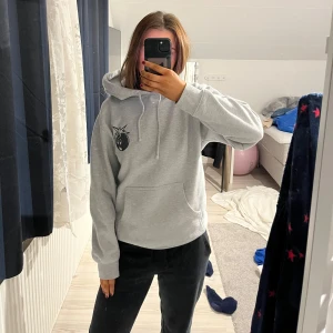 Grå hoodie med tryck - Säljer en grå hoodie med ett coolt tryck av en bomb på både framsidan och baksidan. Den har en stor ficka framtill och justerbar huva med snören. Perfekt för en avslappnad stil.