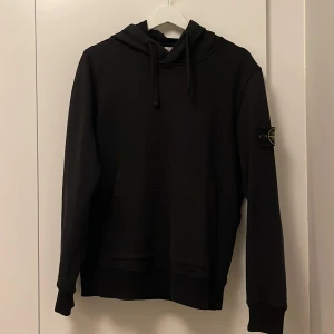 Svart hoodie från Stone Island - Säljer en svart hoodie från Stone Island pga att den inte längre används🩷Tröjan har en klassisk huva och en stor magficka. Hoodien är i väldigt gott skick utan några defekter. Storlek S🫶🏼