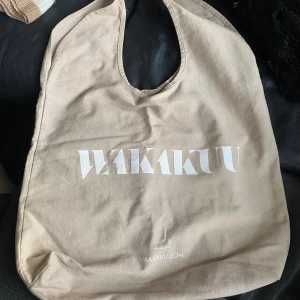 Beige wakakuu väska - En beige wakakuu tygpåse, använd fåtal gånger så bra skick. Köpt från Wakakuu affären i Hovås.