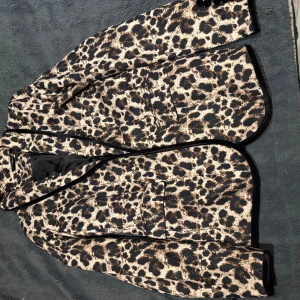 Leopardmönstrad kavaj - Snygg leopardmönstrad kavaj med svarta detaljer. Perfekt för att sticka ut med stil. Kavajen har en klassisk passform och är helfodrad för extra komfort.