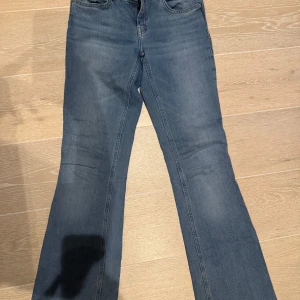 Blå jeans från Lager 157 - Säljer ett par klassiska blå Lager 157  jeans i modell low boot. De har en bootcut-stil och är perfekta för en avslappnad look. Jeansen är lågmidjade och tillverkade i jeansmaterial.