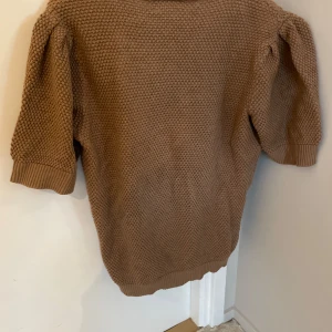 Brun/beige stickad tröja från VILA - Säljer en mysig brun stickad tröja från VILA. Tröjan har en grovstickad textur och trekvartsärmar med ribbade muddar. 
