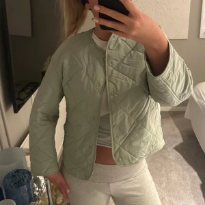 Grön quiltad jacka från MNG - Snygg grön quiltad jacka från MNG med knappar framtill. Jackan är vattenavvisande och har en stilren design med långa ärmar. Ny pris 600kr