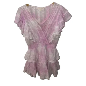 Ljusrosa klänning från LoveShackFancy - Charmig ljusrosa klänning från LoveShackFancy med volanger och spetsdetaljer. Klänningen har korta ärmar, perfekt för en romantisk look med volanger. 