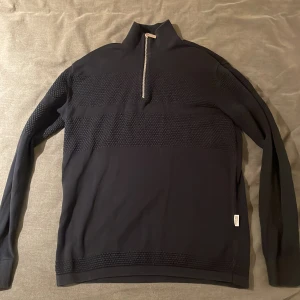 Mörkblå tröja med dragkedja från Selected Homme - Snygg mörkblå tröja från Selected Homme med halv dragkedja och ribbade detaljer. Perfekt för en stilren look med långärmad design och texturerat mönster över bröstet. Kan gå ner i pris vid snabb affär!!