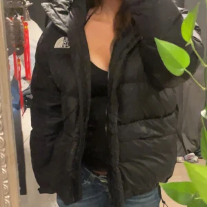 Svart dunjacka från The North Face - Säljer en svart dunjacka från The North Face. Jackan har en pufferdesign med dragkedja och en hög krage för extra värme. Perfekt för kyliga dagar. Storlek L. 