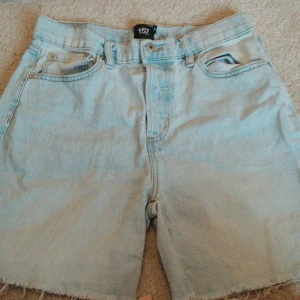 Ljusblå jeansshorts från  lager 157 - Säljer ett par ljusblå jeansshorts från lager 157. De har en klassisk femficksdesign och råa kanter vid bensluten för en avslappnad look. Perfekta för varma sommardagar!