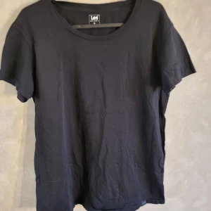 Svart t-shirt från Lee - Säljer en klassisk svart t-shirt från Lee i storlek M. Den har en rund halsringning och korta ärmar, perfekt för en enkel och stilren look. Passar till det mesta och är ett måste i garderoben.
