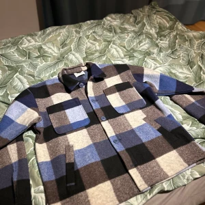 Rutig overshirt från Valente - Säljer en snygg rutig overshirt från Valente i storlek L. Den har ett coolt mönster i blått, svart, brunt och beige. Perfekt för höst och vår! Jackan har långa ärmar och knappar framtill samt två praktiska bröstfickor. Superbra skick och redo för nya äventyr! 🍂 skriv min minsta fundering. Pris går att diskuteras😊