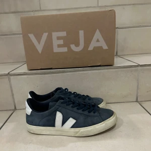 Blå sneakers från Veja, Storlek 42 passar 43 - Säljer ett par snygga blå sneakers från Veja i bra skick. De har en vit sula (som är lite slitna) men annars är skorna i väldigt bra skick. Ny pris 1300 kr