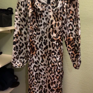 Leopardmönstrad klänning - Snygg leopardmönstrad klänning i ett glansigt material. Perfekt för en utekväll eller fest! Klänningen har långa ärmar och en figurnära passform som framhäver dina kurvor. Den är både trendig och bekväm, vilket gör den till ett måste i garderoben.