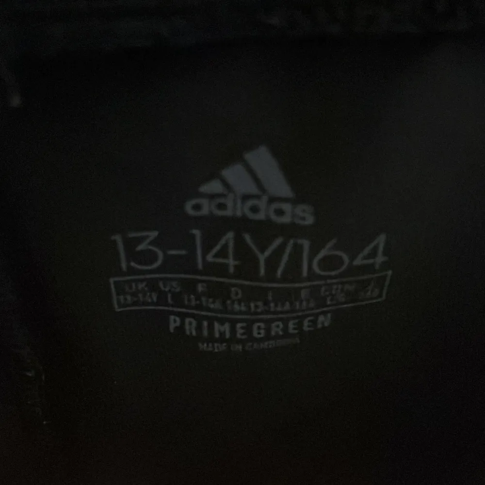 Säljer ett par svarta träningsbyxor från Adidas i storlek 13-14 år. Byxorna har de klassiska tre vita ränderna längs sidorna och är tillverkade i Primegreen-material. Perfekta för träning eller vardagsbruk!. Jeans & Byxor.