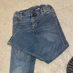 Blå jeansbyxor Polarn och Pyret 8 år - Säljer ett par klassiska blå jeansbyxor i bra skick från Polarn och Pyret. De har en normal passform (lite smal men inte skinny) och är perfekta för vardagsbruk. Byxorna har en knapp och dragkedja framtill samt fickor både fram och bak. 