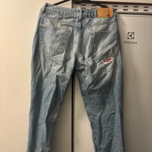 Ljusa slitna jeans - Säljer ett par ljusa Lager 157  jeans med coola slitningar på framsidan. De har en klassisk femficksdesign och en bekväm passform. Perfekta för en avslappnad stil med en t-shirt eller hoodie. Passar både till vardags och fest!