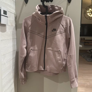 Beige hoodie från Nike - Säljer en snygg beige hoodie från Nike i storlek XS. Den har en dragkedja framtill och en bekväm huva. Perfekt för höst och vår, med långa ärmar och en stilren design. Passar både till träning och vardags.