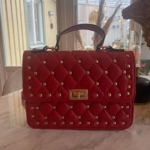 Nitväska  - Röd nitväska köpt på plick. Det långa bandet går att ta av/på . Några jätte små defekter där lite tråd gått upp o knäppet  lite repigt som man ser på bild 3& 4