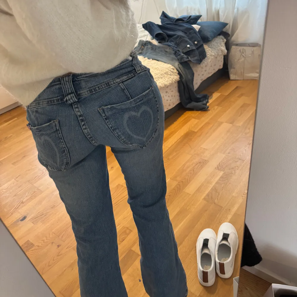 Säljer ett par snygga blå bootcut jeans i bra skick. De är lågmidjade och har en söt hjärtdetalj på bakfickorna. Perfekta för både vardag och fest! 💙jag är 173cm lång 🥰 finns en liten fläck längst ner på baksidan av vänstra benet som säkert är lätt att få bort i tvätten . Farkut & Housut.