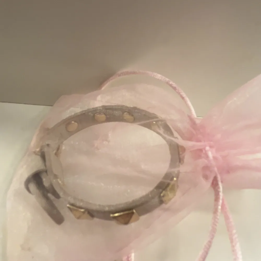 Armband i beige med guldiga nitar från Byus. Armbandet har justerbar passform. Fick detta armband förr förra året och har aldrig använt det. Armbandet är köpt på Byus i Lidingö centrum och nypriset är 500kr. Armbandet kommer inte till användning därför jag säljer det🤍 . Accessoarer.