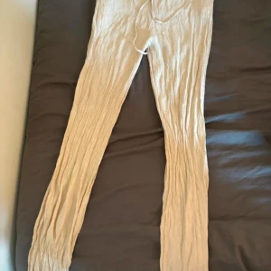 Beige byxor från Zara - Säljer ett par beige byxor från Zara i storlek M. De är gjorda i ett lätt och luftigt material med en skön loose passform. Perfekta för varma sommardagar eller avslappnade tillfällen. Byxorna har en elastisk midja med snörning för extra komfort.