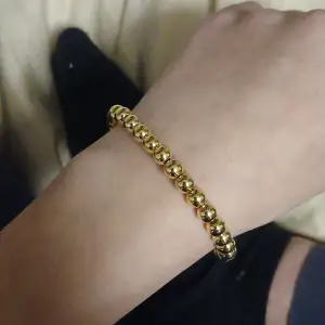 Snyggt och stilrent armband i guld med glänsande pärlor. Perfekt för att ge en elegant touch till vilken outfit som helst. Passar både till vardags och festliga tillfällen. Ett måste för smyckesälskare!