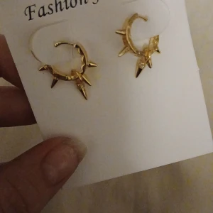 Guldörhängen med spetsdetaljer - Snygga guldörhängen med coola spetsdetaljer som ger en edgy look. Perfekta för att piffa upp vilken outfit som helst, oavsett om det är till vardags eller fest. De är i nytt skick och redo att bäras av någon som vill sticka ut!
