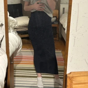 Mörkblå långkjol - Säljer en elegant mörkblå långkjol i mycket bra skick. Kjolen har en tight passform som framhäver figuren och är perfekt för både vardag och fest. Materialet är mjukt och stretchigt, vilket gör den bekväm att bära hela dagen. Passar perfekt till en enkel topp eller en mer uppklädd stil.