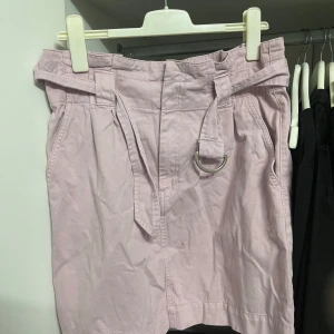Ljusrosa kjol från H&M - Säljer en superfin ljuslila kjol från H&M i storlek L. Kjolen har ett bälte med metallring som ger en snygg detalj och perfekt passform. Den är gjord i ett bekvämt bomullsmaterial, perfekt för vår och sommar. Passar både till vardags och fest! 🌸