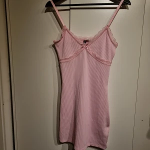 Rosa ribbad klänning - Säljer en söt rosa ribbad klänning med spetsdetaljer. Storlek S. Ej använd.