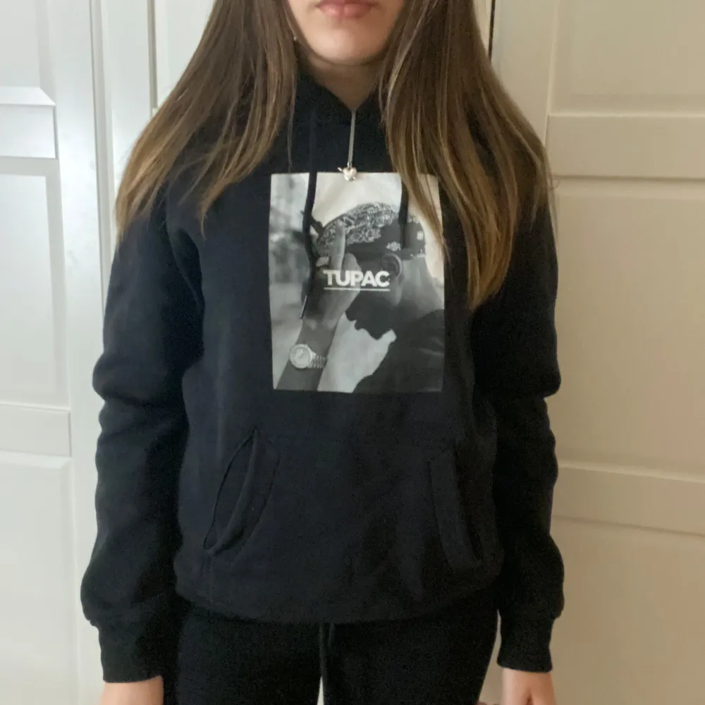 Säljer en svart hoodie med ett coolt Tupac-tryck på framsidan. Den har en klassisk passform med långa ärmar och en bekväm huva med dragsko. Perfekt för vardagsbruk eller när du vill ha en avslappnad stil. Passar bra till jeans eller mjukisbyxor. Den är lite liten i storleken så skulle säga storlek S. Hoodies.