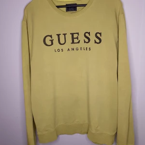 Gul tröja från Guess storlek XL - Säljer en snygg gul tröja från Guess med texten 'Los Angeles' tryckt på framsidan. Tröjan är i slim fit och har långa ärmar. Perfekt för en avslappnad stil och passar bra till både jeans och shorts. Den är i mycket bra skick och redo för en ny ägare!