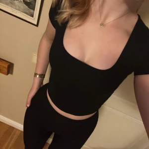 Svart croppad topp - Säljer en svart croppad topp med korta ärmar och urringning. Den är stretchig och passar XS-M 🖤 Toppen är använd endast en gång och är u nyskick. Skriv för frågor! 