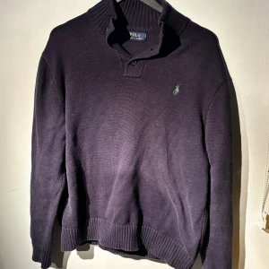 Mörkblå tröja från Ralph Lauren - Säljer en snygg mörkblå tröja från Ralph Lauren i Medium med klassisk broderad logga i grönt. Tröjan har en hög krage med knappar och är perfekt för kyliga dagar. Den är i bra skick och passar både till vardags och lite finare tillfällen. Perfekt för höst och vinter! Köpt för 2000kr i London. Tveka inte att höra av dig om du har frågor eller vill ha fler bilder 