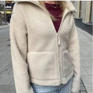 Beige teddyjacka med dragkedja - Mysig beige teddyjacka i syntetmaterial med dragkedja framtill. Perfekt för kyliga höst- och vinterdagar. Jackan har en normal passform och långa ärmar STORLEK S🩷