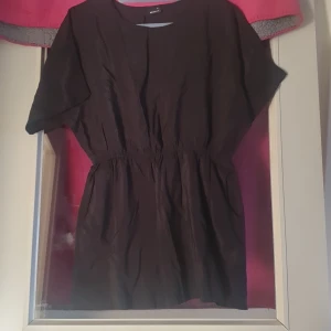 Svart top med korta ärmar - Säljer en stilren svart top  med korta ärmar och elastisk midja för en bekväm passform med fickor vid sidan . Perfekt för både vardag och festliga tillfällen