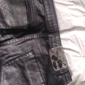 silvriga bootcut jeans - Säljer ett par snygga silver bootcut jeans i bra skick. De har en klassisk femficksdesign och en cool etikett på baksidan. Perfekta för både vardag och fest! 🖤