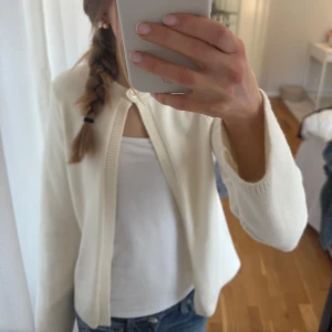Vit kofta från Gina Tricot - Säljer en superfin ljus beige kofta från Gina Tricot i storlek XS. Den är i mycket bra skick och har en enkel knapp framtill. Perfekt stilren kofta och den är riktigt mysig att ha på sig. Passar till alla tillfällen! 🤍