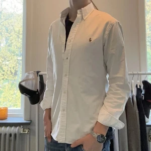 Polo ralph lauren skjorta - Upptäck tidlös elegans med denna Polo Ralph Lauren skjorta! Denna vita skjorta är i absolut toppskick – 10/10, använd endast en gång. Inga fläckar eller skador. Ganska liten i storleken. Nypriset var 1500 kr, nu har du chansen att få den till ett fantastiskt pris. Kontakta mig gärna om du har några frågor!