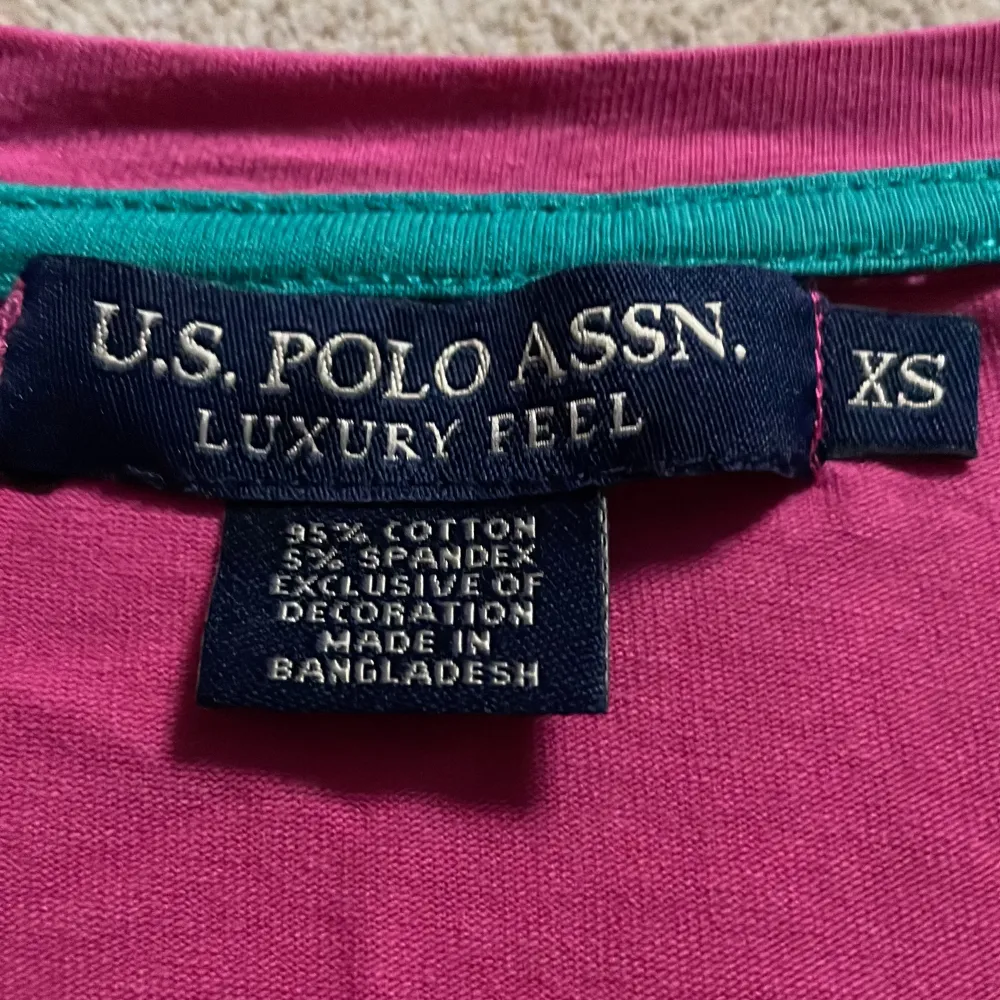 Säljer en snygg rosa t-shirt från U.S. Polo Assn. i storlek XS. Den är gjord av bomull och spandex för en skön och stretchig passform. T-shirten har en v-ringning och ett broderat logotypmärke på bröstet. Köpt i New York. T-shirts.