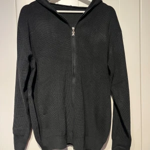 Svart stickad hoodie med dragkedja - Säljer en svart stickad hoodie i mycket bra skick. Köpt second hand utan lappar.