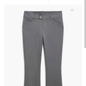 Grå kostymbyxor bootcut - Säljer ett par stilrena grå byxor i bootcut-modell. De har en klassisk design med knappar och dragkedja framtill. Perfekta för både vardag och fest! 🩶