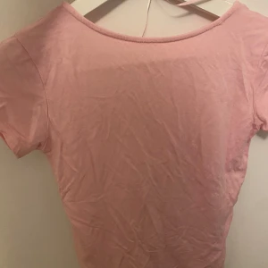 Rosa kortärmad topp - Säljer en söt rosa topp i storlek XS. Den har en rygglös och har korta ärmar, perfekt för sommardagar. Materialet är mjukt och bekvämt, vilket gör den idealisk för både vardag och fest. Toppen är i bra skick och redo för en ny ägare! Storlek xs men den är stretchig så kan passa S.  Köparen står för frakten