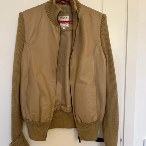 Beige jacka från Uniqlo - Säljer en snygg beige jacka från Uniqlo. Den har långa ärmar i stickat material och en kropp i syntet. Perfekt för höst och vår med sin stilrena design och bekväma passform. Dragkedja framtill för enkel stängning. #vintage