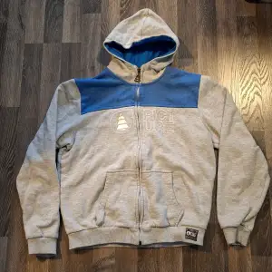 Säljer en snygg och bekväm grå hoodie från Picture med blå detaljer. Den har en dragkedja framtill och en stor luva med blått foder. Perfekt för kyliga dagar eller som en casual vardagströja. Den är i bra skick och redo för nya äventyr!