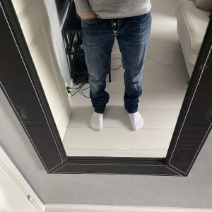 Replay jeans  - Säljer ett par snygga mörkblå jeans med knappar framtill. De har en klassisk straight fit och är perfekta för både vardag och fest. Jeansen är i bra skick och har en stilren design med fem fickor.30/32