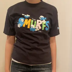 Säljer en ny svart t-shirt från Zara med ett färgglatt Smurfarna-tryck på framsidan. T-shirten är i bomull och har korta ärmar. Perfekt för en avslappnad stil eller för att visa din kärlek till Smurfarna! 🖤💙